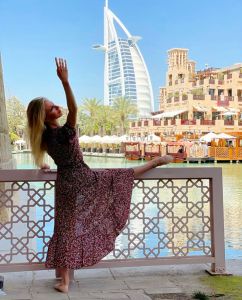 A photo of guest blog post author April Lorenzi. She poses with her leg up on a decorative railing, arm lifted, against a stunning background.